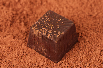 Chocolate sweets with cocoa, on brown background