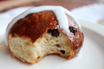 Delicious hot cross bun on simple white plate