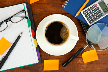 Cup of coffee on worktable covered with documents close up
