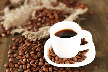 Cup of coffee and coffee beans on wooden background