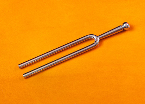 Tuning fork on a reflective wooden background.