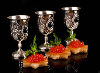 Pancakes with red caviar on silver ware