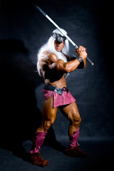 Muscular man in an image of a barbarian with a raised sword.