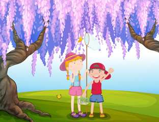 Une fille et un garçon attrapant un papillon au parc
