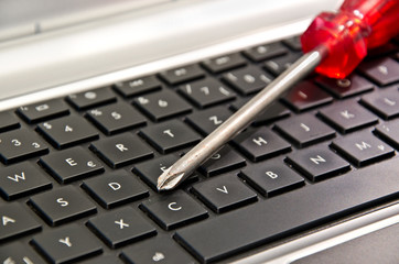 Schraubenzieher auf Computertatstatur liegend (Symbol für Computerreparatur oder Wartung)