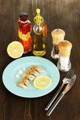 Dish of herring and spices on wooden table close-up