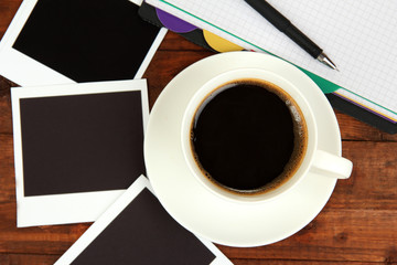 Cup of coffee on worktable covered with photo frames close up