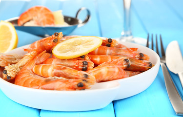 Shrimps with lemon on plate on wooden table close-up