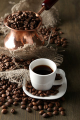 Cup of coffee and pot on wooden background