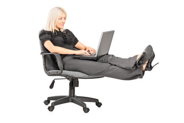 Young woman sitting on office chair with her legs up and working