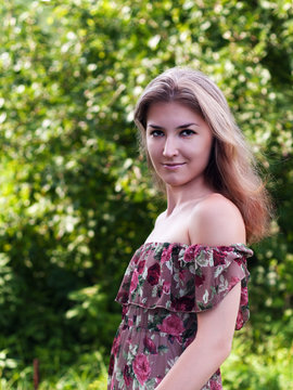 Beautiful girl in floral dress stand in garden.