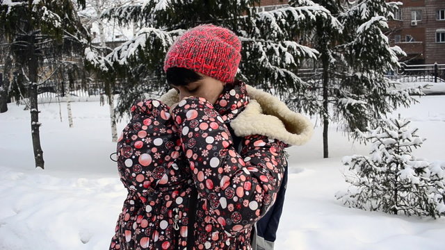 Young mother walking in a winter park with a baby
