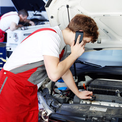 Master mechanic in a garage calls a customer