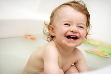 Irresistible baby smiling in the bath while playing