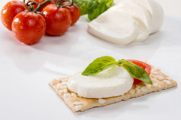 Crackers with mozzarella, basil and tomato