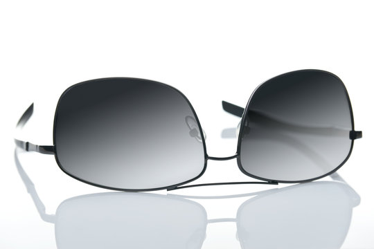 Sunglasses lying on the reflecting white desk.