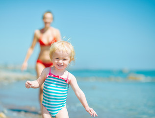 Naklejka premium Mother and baby girl playing on sea shore
