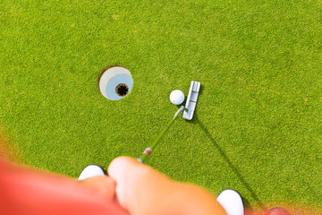 Golf player putting ball in hole