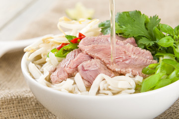 Pho Bo - Vietnamese rice noodle soup with beef, herbs and chili