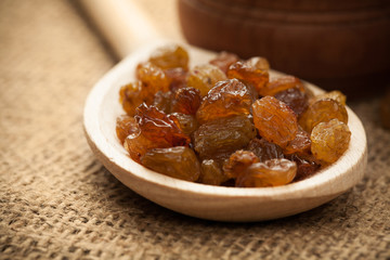 Raisins on a wooden spoon on a burlap