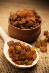 Raisins on a wooden spoon on a burlap