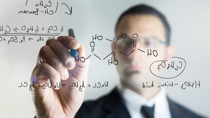 man writing chemical formulas over a transparent screen