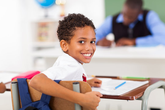 cute elementary schoolboy looking back in classroom