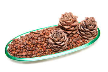 Three pine cones and pine nuts in a glass rook