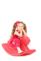 Little girl in a red dress relaxing  on a rocking toy