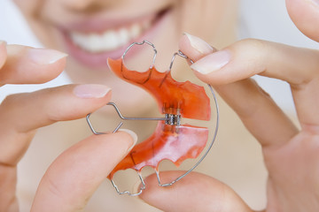smiling girl holding braces for teeth