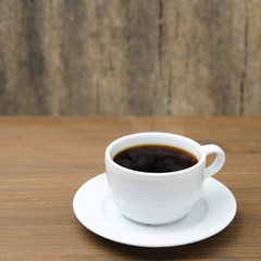 cup of coffee with steam on a wooden table