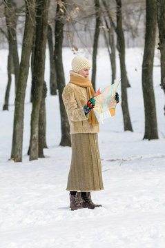 A woman lost in the forest in winter is reading a map to find her way home