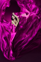 Woman in violet waving silk dress. Dancing.