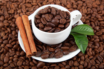 Cup with coffee beans and cinnamon sticks.