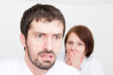 Portrait of upset young couple sitting seperately in the bedroom