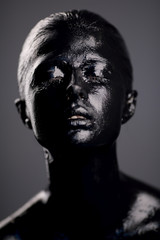girl in black paint on dark background