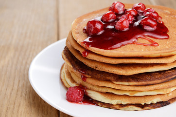 Delicious pancakes with raspberries on the wooden kitchen table