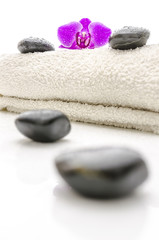 Obraz na płótnie Canvas Masaż kamieniami i fioletowy kwiat orchidei na ręcznik