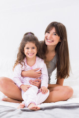 Mother and daughter sitting on bed