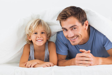 Father and his son lying under the duvet