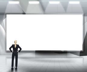 Fototapeta premium Businesswoman looking up at large blank screen under lights