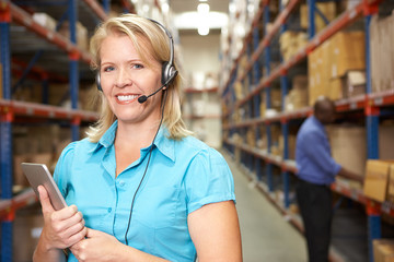 Businesswoman Using Headset In Distribution Warehouse