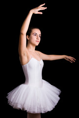 Fototapeta premium Teen girl ballet dancer standing in a tutu on a black background