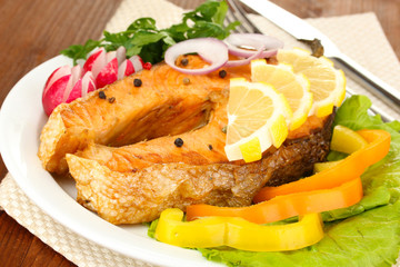 Appetizing grilled salmon with lemon and vegetables close up