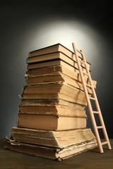 Old books and wooden ladder, on grey background