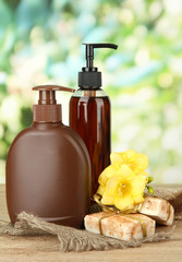 Liquid and hand-made soaps on wooden table, on green background