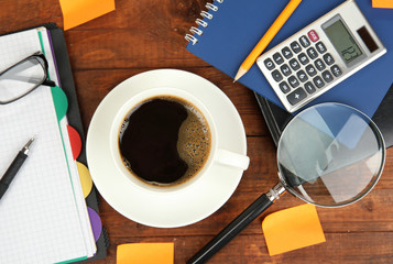 Cup of coffee on worktable covered with documents close up