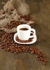 Cup of coffee and coffee beans on wooden background
