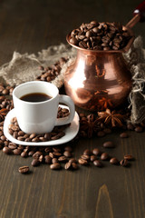 Cup of coffee and pot on wooden background