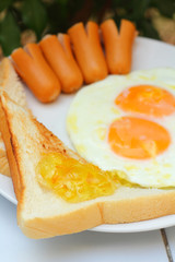 Fried eggs with hotdog and toasts
